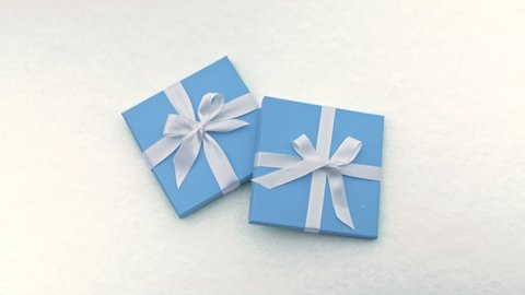 Beautiful light pastel blue boxes with white satin ribbon and simple bows isolated on snow background. Background footage symbolizing love, Valentine Day, Womens Day, Birthday, Wedding Anniversary 6K