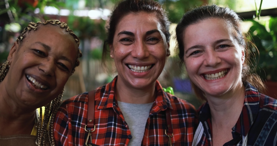 Multiracial women working together inside nursery greenhouse while smiling on camera - Green market concept Royalty-Free Stock Footage #1087115960