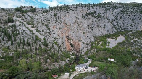 Aerial drone view of Blagaj City under the cliff, historical ottoman dervish lodge built under the rock and on the bank of the Buna river