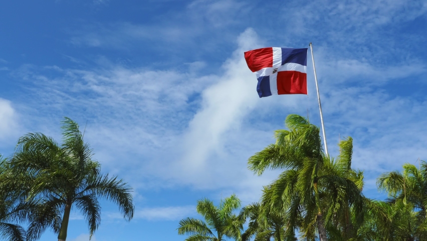 Flying and waving flag of Dominican Republic on wind on blue sky background Royalty-Free Stock Footage #1087118576