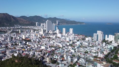 Nha Trang, Vietnam - February 6, 2021: Aerial view of Nha Trang and scenic wooded mountains around the city, Vietnam. Drone flying over the coastal city and amazing green hills.