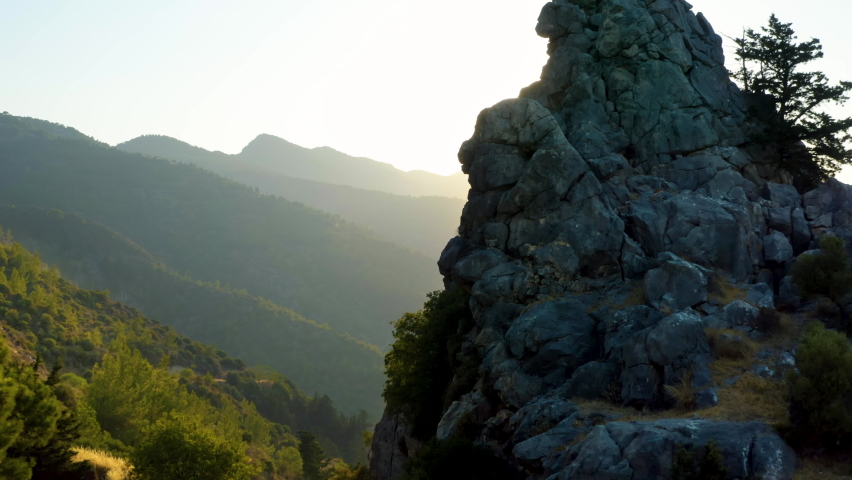 Moving away from a stone formation in a sunlit Cyprus valley