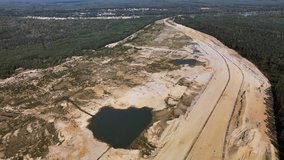 Aerial high altitude shot over the huge open-pit sand quarry causing environmental problems by lowering the subcutaneous water level