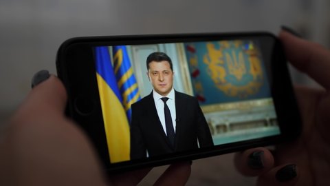 girl watches the speech of the President of Ukraine Volodymyr Zelensky on smartphone. News about tensions between Ukraine and Russia. Russian aggression. Threat of war. CHERNIGOV UKRAINE FEBRUARY 2022