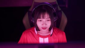 Handheld, portrait of a asian female gamer in headphones, plays a video game, cyber sportsman at the game, communication between players, playing as a team, tournament.