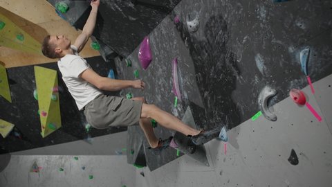 Climber training on a climbing wall, practicing rock-climbing, mountaineer training.