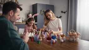 Cheerful caucasian family of four people decorating easter eggs at home. Shot with RED helium camera in 8K  