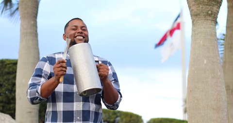 dominican man playing guira merengue with dominican flag 