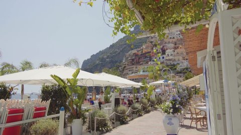 Positano, Italy - 1.07.2021: View of the beach, relaxing tourists and the hill during a sunny summer. Amalfi Coast, coastline, sea, beautiful day, gimbal camera move - 4K Video Footage