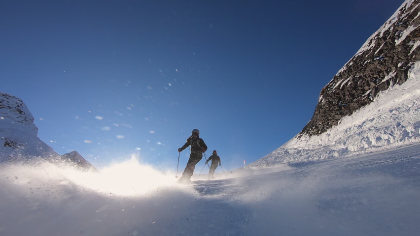 Panorama alpine skiing of two male ski professionals in the swiss mountains with amazing view on the wild mountain range covered with fresh snow. Cinematic slow motion skiing in winter. 4K PRORES 422 Royalty-Free Stock Footage #1087143062