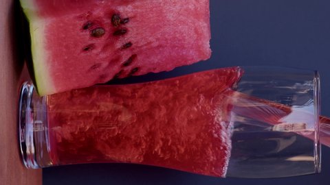 A slice of watermelon juice in cold ice on a grey background, ice falls on the watermelon slowly from the top. Slow motion footage, 8K downscale,  filmed on high speed cinema camera. 4K.
