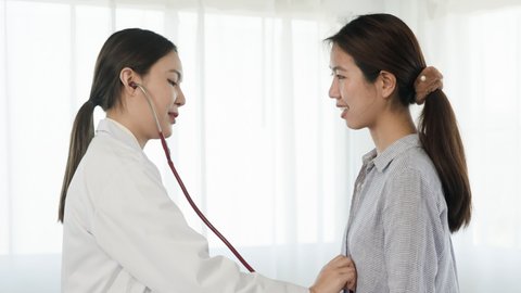 4K, An Asian female doctor uses a stethoscope against the patient's chest to listen to the heart sound to know the patient's condition. Concept Health and Medicine
