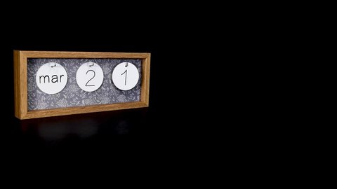 A wooden calendar block showing the date March 21st with a mans hand putting on and taking off the metal discs with the date and month on them, filmed in 8k quality 
