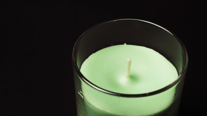 Burring aroma candle on black background close up. Wooden stick lights candle, filmed on high framerate. Ignition of green aroma candle in the glass | Shutterstock HD Video #1087149533