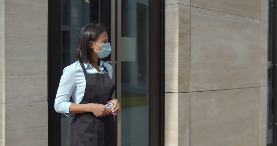 businessman showing vaccination passport at restaurant entrance. Business cafeteria worker in mask check temperature or vaccination certificate of customer