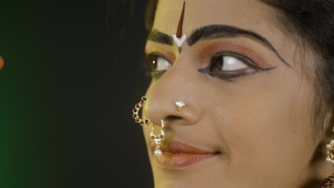 Close up shot of bharatanatyam dancer doing eye moments or drishti bheda by looking at camera - concept of indian culture, traditional classical dancer.