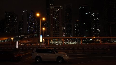 Dubai, UAEmirates - febr 17 2022: Nighttime Time lapse of car traffic on Sheikh Zayed Rd along the Dubai Marina with a Marina Tram passing by and two Red Line Metro’s  in the background.
