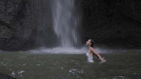 Pure happiness in nature, woman enjoying fresh tropical waterfall and lake in rocks, calm relaxation