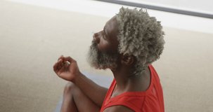 Video of african american senior man meditating. retirement lifestyle, spending time alone at home concept digitally generated video.