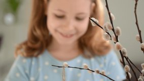 Close up video of girls hands hanging easter eggs on willow branch at spring time