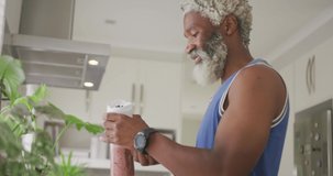 Video of african american senior man preparing smoothie. retirement lifestyle, spending time alone at home concept digitally generated video.