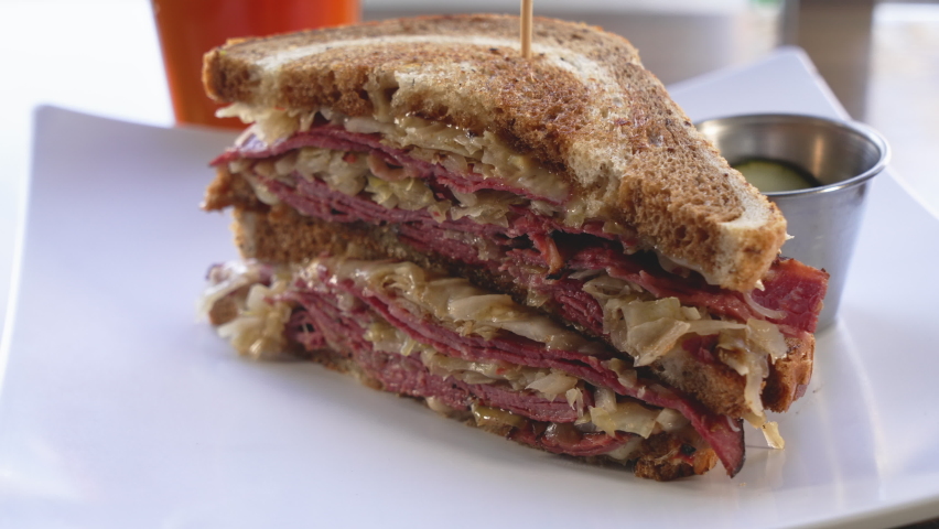 A classic stacked deli reuben sandwich on marble rye bread, slider close up 4K