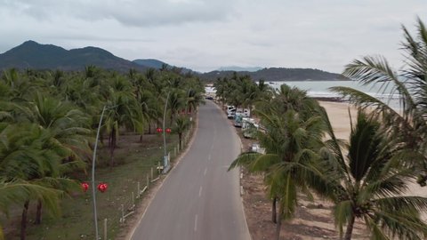 View of tropical road with palm trees by the beach side with parked camper vans and Recreation vehicles. Hainan island, China.