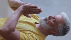 a man meditates and engages in spiritual practices. senior yoga an adult white-haired European in a yellow T-shirt sits on the floor in a lotus position and meditates. relaxation after sports or yoga