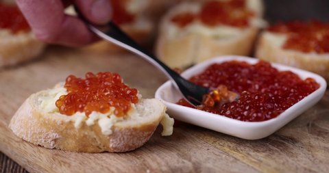 a spoon is placed in the caviar, natural red salmon caviar with baguette and butter, making sandwiches snacks from red caviar, baguettes and butter
