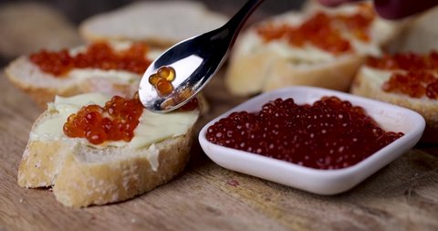 caviar is placed on a baguette with butter, natural red salmon caviar with baguette and butter, making sandwiches snacks from red caviar