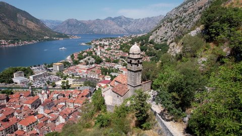 Aerial Pass Over Medieval Stone Mountain Church Tower of Our Lady of Remedy to Reveal Old Town of Kotor Montenegro in Sea Valley Below Summer Day Drone 4k