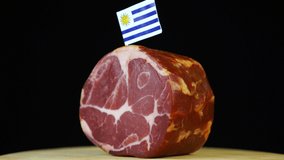 Delicious smoked tenderloin with small flag of Uruguay, piece of meat rotating on balck background. - Powered by Shutterstock - Get 15% off with code: PIKWIZARD15