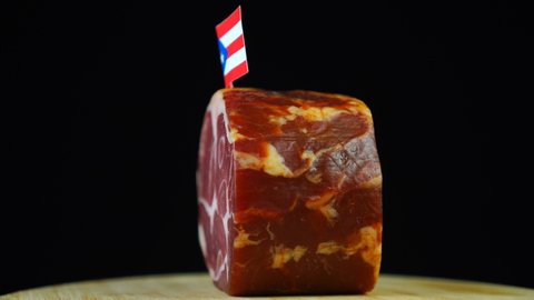 Delicious smoked tenderloin with small flag of Puerto Rico, piece of meat rotating on balck background.