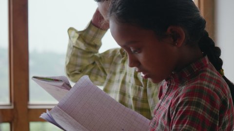 close up shot of an Indian Asian little girl in village primary School uniform holding a Notebook in her hands and reading from it thoroughly. Concept of Rural Girl Education or child literacy Video stock