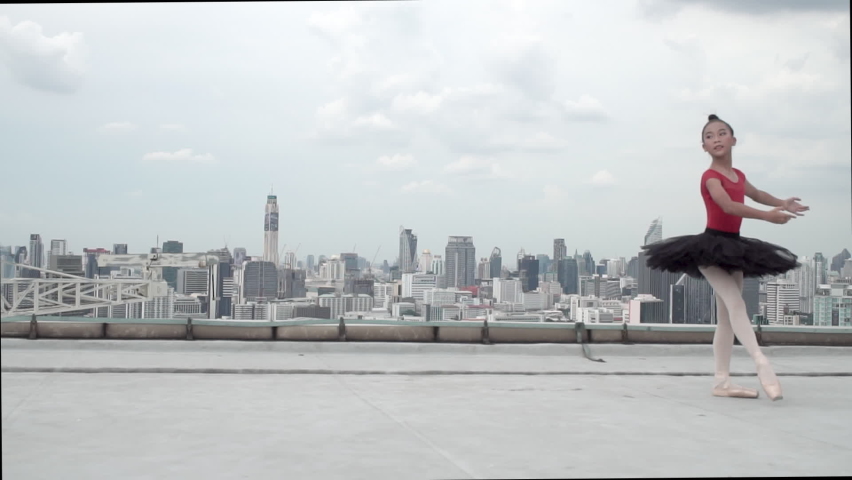 Attractive Asian dancer little children girl wearing black tutu dress dance ballet on rooftop point leg balance body with sky clouds. Active girl kid dance performer ballet around rooftop. Slow-motion Royalty-Free Stock Footage #1087189988