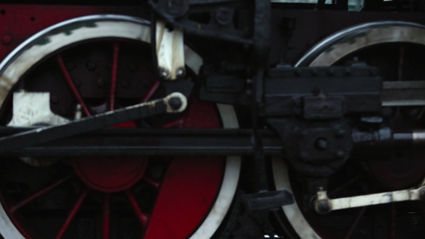 Close up of steam locomotive train wheels with steam visible and fire ...