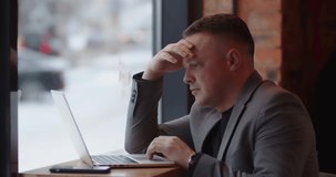 Man exploring work online sitting in cafe, focused. Browse information on laptop