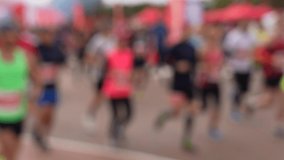 Blurry defocused silhouettes of many people running together outdoors during sport marathon. Male and female silhouettes of people run. Abstract slow motion 4k video background