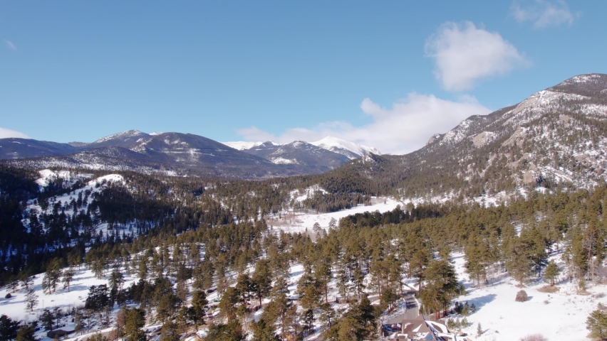 Estes Park, Rocky Mountains National Park Colorado. Drone Aerial View Flying Over Green Pine Trees in Snowy Mountain Valley Slope During Sunny Day.