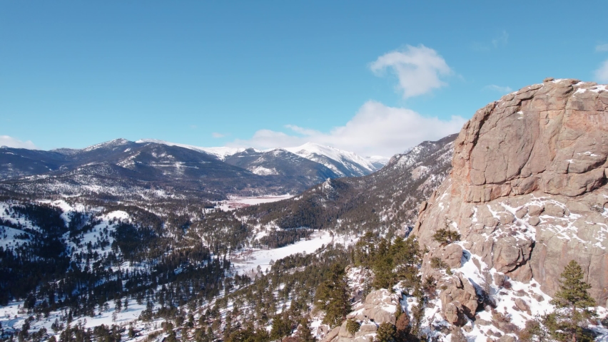 Estes Park, Rocky Mountains National Park Colorado. Drone Aerial View Of Snow Covered Alpine Mountain Range Valley During Sunny Day Flying Passed Mountain Ridge.