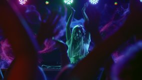 DJ plays disco music on turntable at night club scene. Partying joyful crowd moves in hip-hop rhythm of funky dance. Trendy girl in bright spot light of multi-color neon. Female dj at concert stage - Powered by Shutterstock - Get 15% off with code: PIKWIZARD15