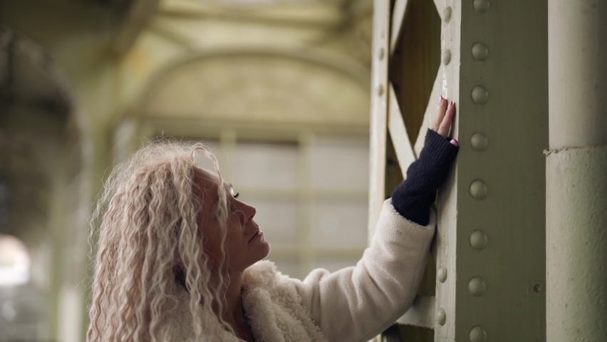 blonde lady in white fur coat and old architecture of metal bridge or station