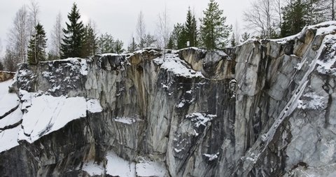 Vertical climb over a marble rock near a frozen marble lake - aerial shot