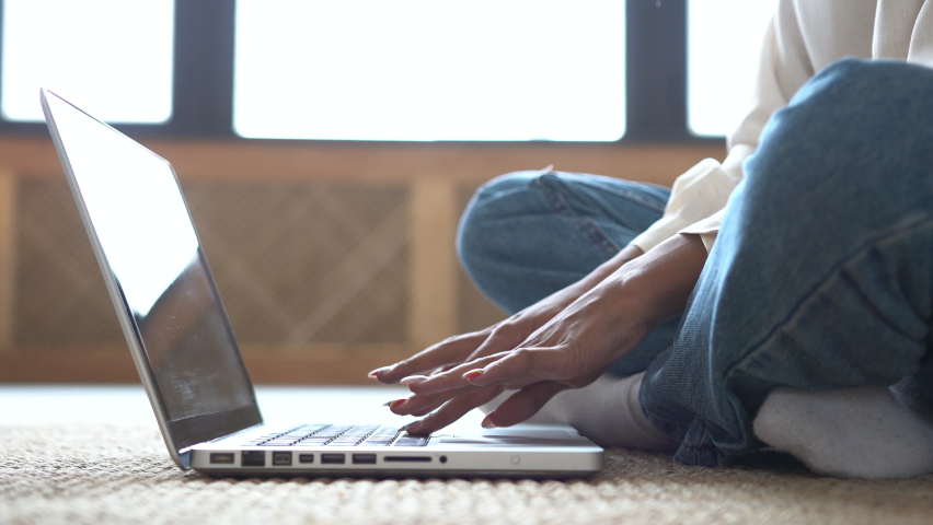 Young woman sitting on the floor, work on freelance, using laptop. Focused girl use computer for study online, female user busy on distance internet job at home