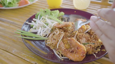 Pad Thai noodle traditional Thailand food. Top view Pad Thai dish on plate coconut trees seaside background. Thai street food vegetarian Bangkok  Asian style. Copy space. Empty space, enter text, comm
