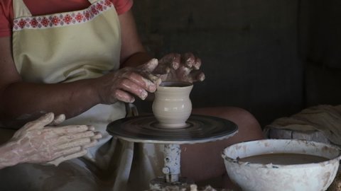 Elder female potter teach young female how to create clay pot on potter's circle. Female potter make ceramic pot on potters wheel.