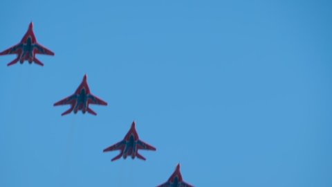 NIZHNY NOVGOROD, RUSSIA - AUGUST 14, 2021: Air Show. Team of military aircraft Mig 29 flying in blue sky and doing stunts - slow motion. Performance, extreme, aerobatic and sport concept
