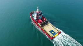 Aerial drone loop video of assistive tug boat cruising near Mediterranean logistics port