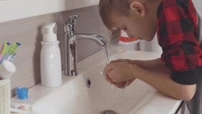 little blond boy washes his face in the bathroom,slow motion