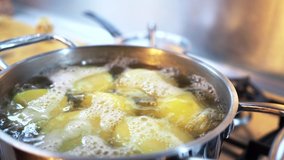 Boiled potatoes in boiling water in a saucepan on a gas stove. Selective focus. 4k video recording